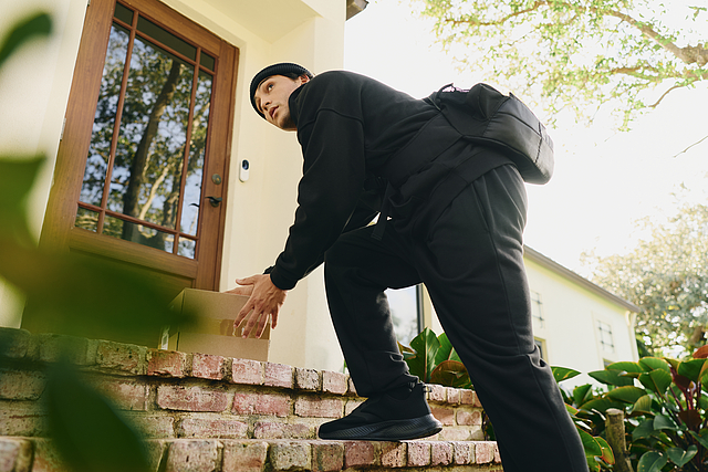 Illustrative scene of a person picking up a package at a front entrance